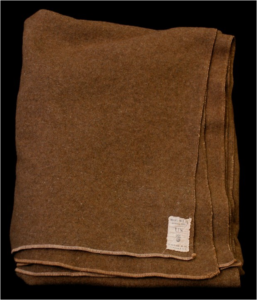 Woolen blanket manufactured by the Mianus Manufacturing Co. of CosCob, under a contract awarded on 20 July 1917. The label has the “flaming bomb” logo of the U.S. Ordnance Dept. (Accession #2016.539)